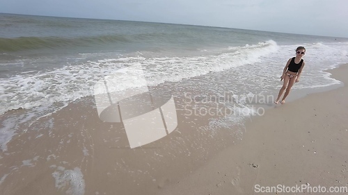 Image of Little kid girl plays on beach shallow water line summer rest during vacations