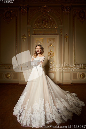 Image of Fashion portrait of beautiful woman in long elegant white dress. Girl with elegant hairstyle. Bridal fashion model in luxury interior in the Baroque style