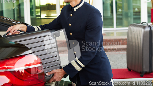 Image of Bellboy taking baggage of guest from thee car to his room