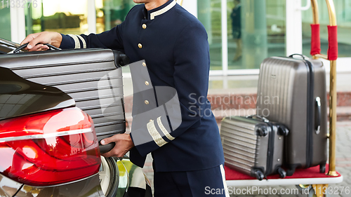 Image of Bellboy taking baggage of guest from thee car to his room