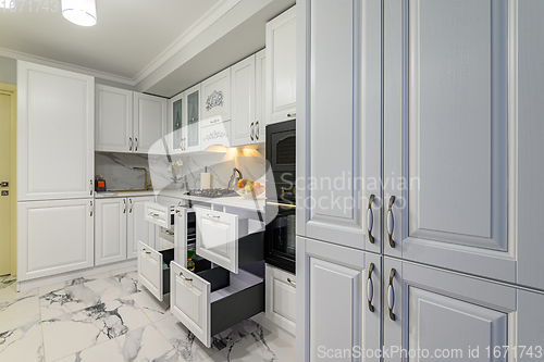 Image of Open drawers with kitchenware at modern white kitchen