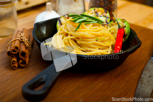 Image of italian spaghetti pasta with zucchini sauce on iron skillet