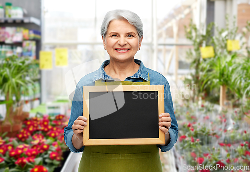 Image of happy senior woman in garden apron with chalkboard