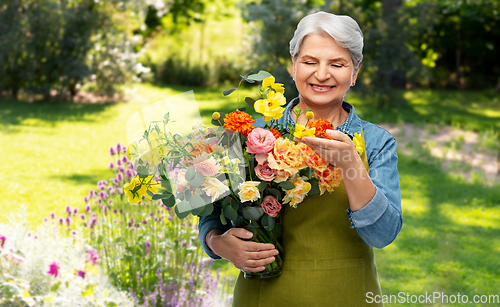 Image of smiling senior woman in garden apron with flowers