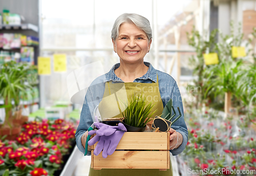 Image of smiling senior woman with garden tools in box