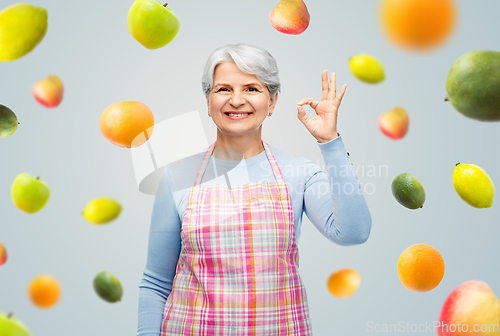 Image of smiling senior woman in apron showing ok gesture