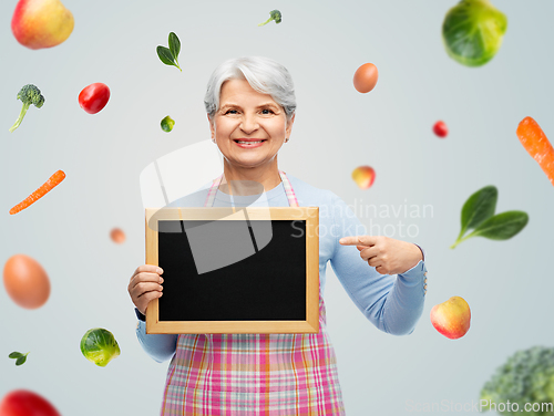 Image of smiling senior woman in apron with chalkboard