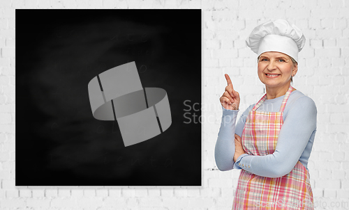 Image of senior woman or chef pointing finger to chalkboard