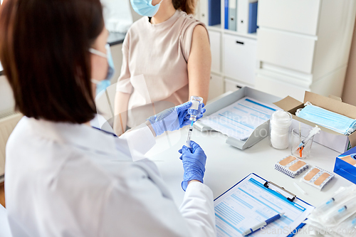 Image of female doctor with syringe vaccinating patient