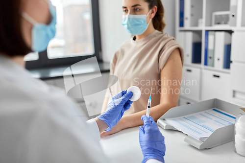 Image of female doctor with syringe vaccinating patient