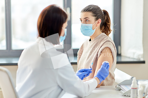 Image of female doctor with syringe vaccinating patient