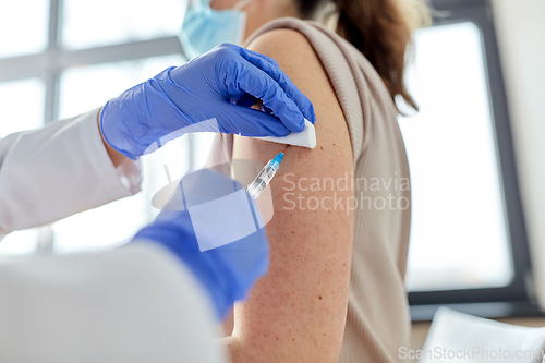 Image of female doctor with syringe vaccinating patient