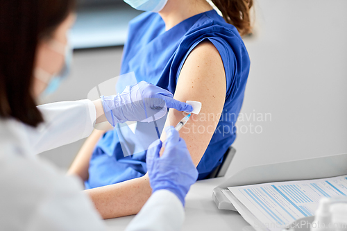 Image of doctor with syringe vaccinating medical worker