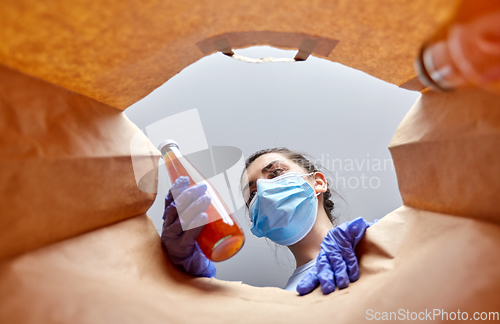 Image of woman in gloves and mask with food in paper bag