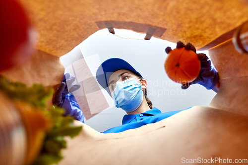 Image of delivery girl in gloves and mask with food in bag