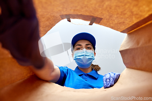 Image of delivery girl in gloves and mask with food in bag