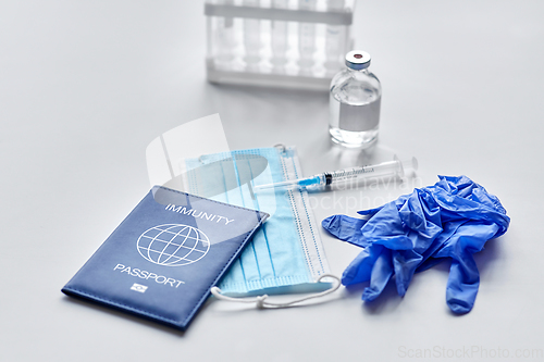 Image of immunity passport, mask, syringe, vaccine on table