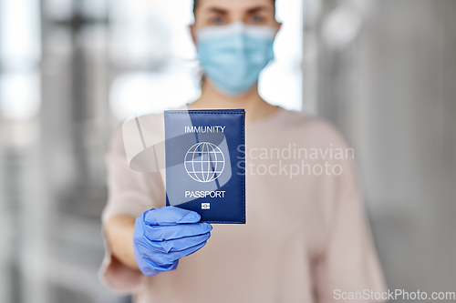 Image of woman in mask and gloves holding immunity passport