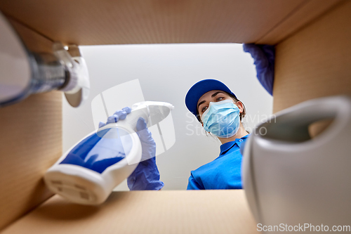 Image of woman in mask packing cleaning supplies in box