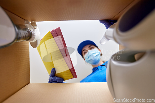 Image of woman in mask packing cleaning supplies in box