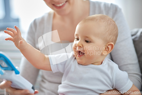 Image of mother with baby playing with toy phone at home