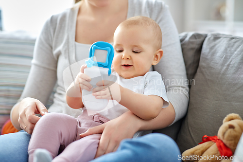 Image of mother with baby playing with toy phone at home