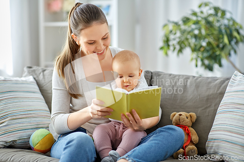 Image of happy mother reading book to little baby at home