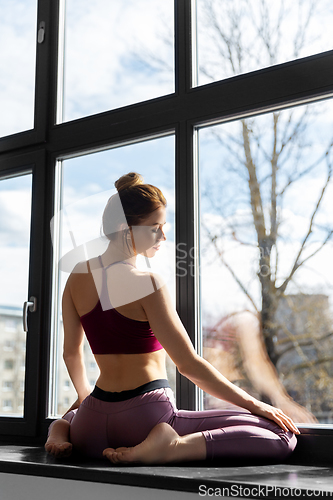 Image of woman doing yoga exercise on window sill at studio