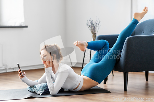 Image of woman with smartphone stretching yoga at home