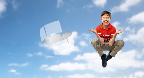 Image of happy young boy flying in yoga pose over sky