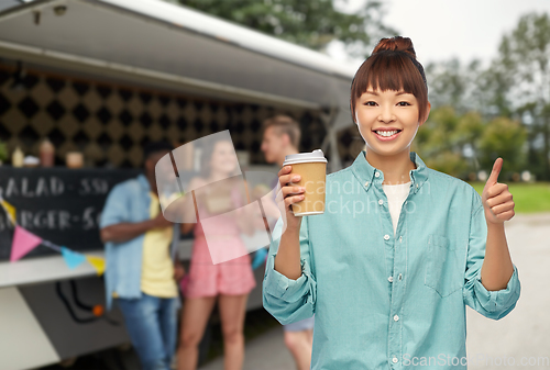 Image of asian woman with coffee cup showing thumbs up