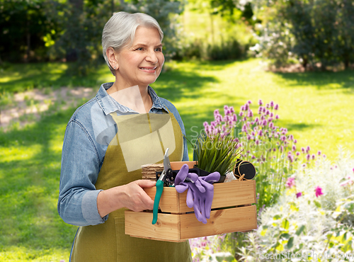 Image of smiling senior woman with garden tools in box