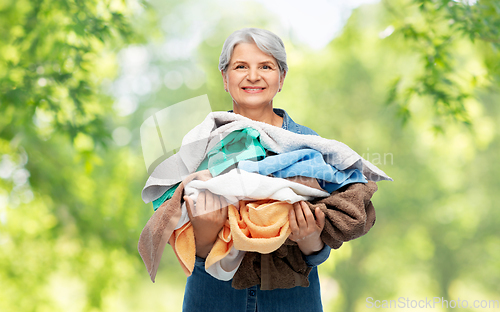 Image of smiling senior woman with heap of bath towels