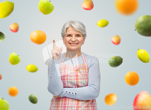 Image of smiling senior woman in apron pointing finger up