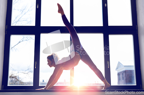 Image of woman doing yoga exercise on window sill at studio