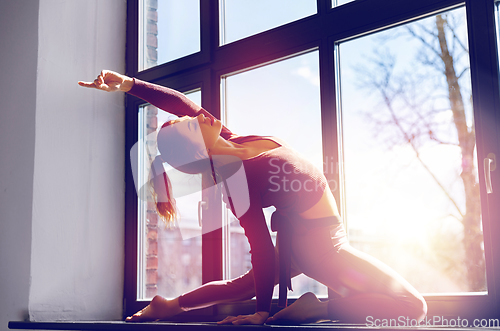 Image of woman doing yoga exercise on window sill at studio