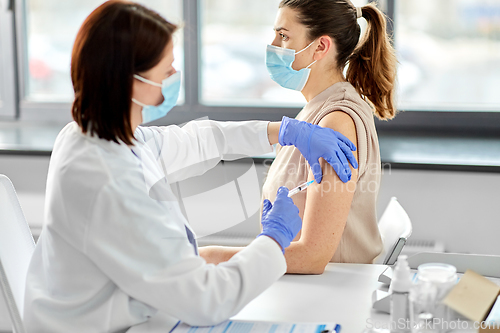 Image of female doctor with syringe vaccinating patient