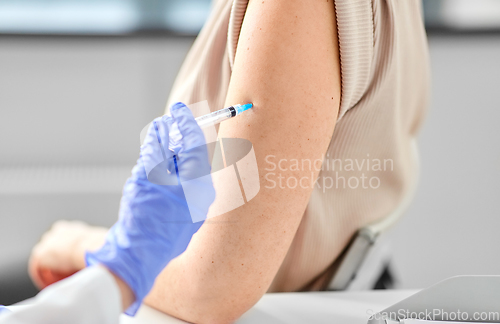 Image of female doctor with syringe vaccinating patient