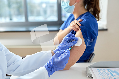 Image of doctor with syringe vaccinating medical worker