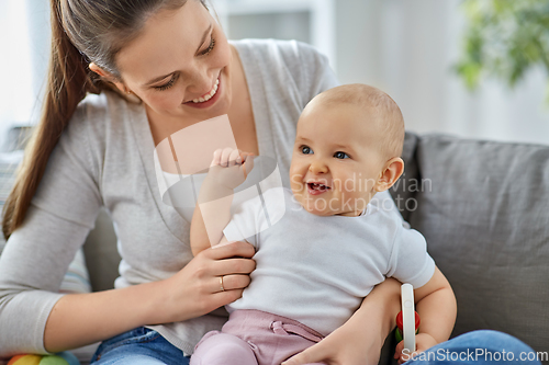 Image of mother and little baby playing with rattle at home