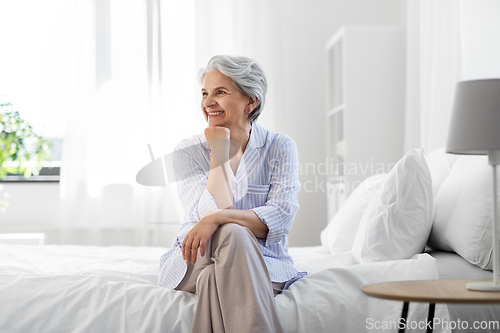 Image of happy senior woman sitting on bed at home bedroom