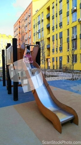 Image of Girl having fun, playing in the slider at the playground.