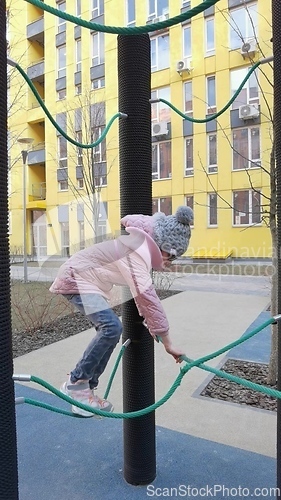 Image of girl plays on the rope park playground. The concept of children's rest in an urban environment.