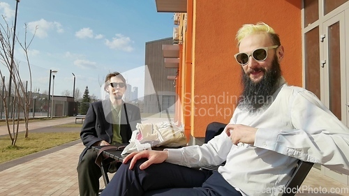 Image of Two young hipster guy sitting in a cafe chatting and drinking coffee smiling