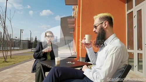 Image of Two colleagues on coffee break in front of business building