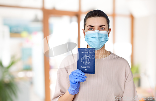 Image of woman in mask and gloves holding immunity passport