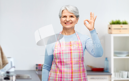 Image of smiling senior woman showing ok gesture at kitchen