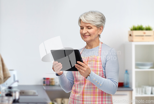 Image of smiling senior woman with tablet pc at kitchen