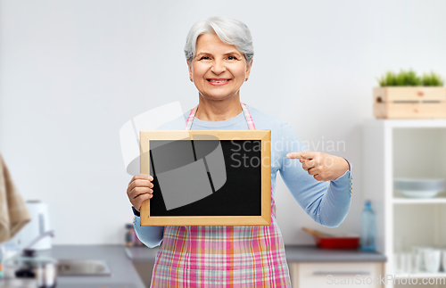 Image of smiling senior woman with chalkboard at kitchen