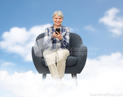 Image of smiling senior woman with smartphone in chair